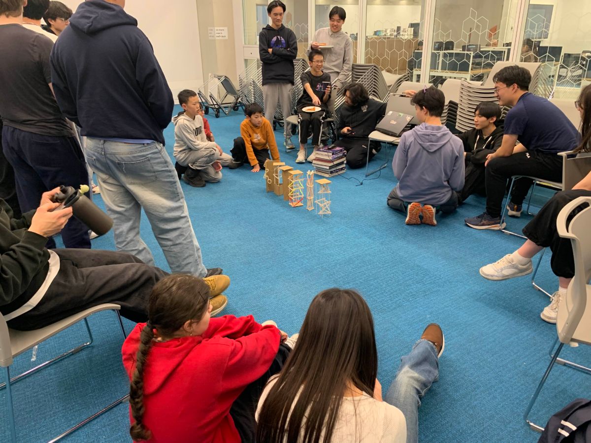Students sitting on the floor around towers being tested