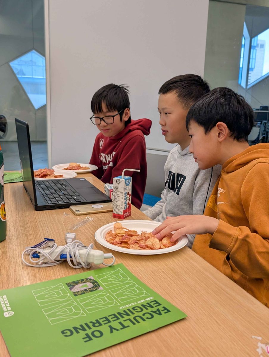 Three middle school students working together on a laptop
