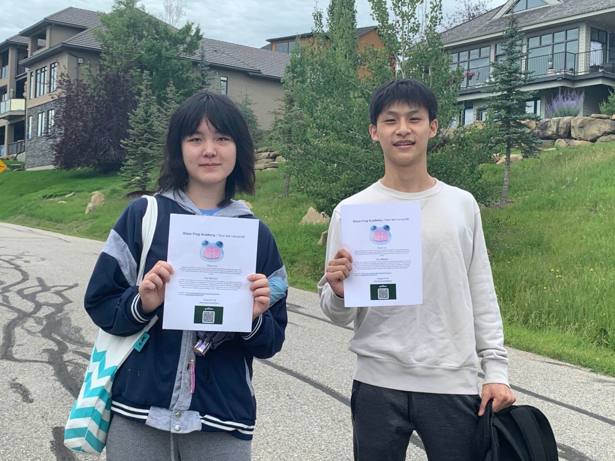 Two GFA team members holding up Glass Frog Academy flyers on a street